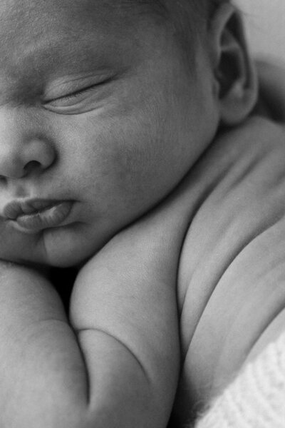 Baby asleep on the bed with a hand tucked under thier chin