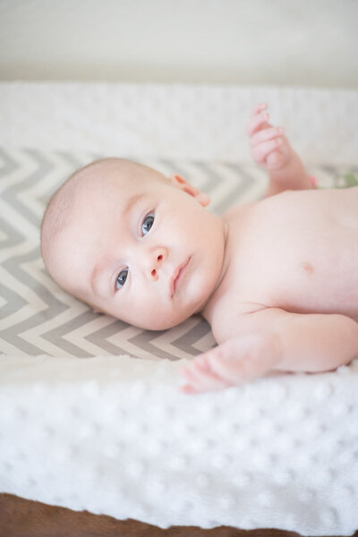 infant laying on a mat looking at the camera