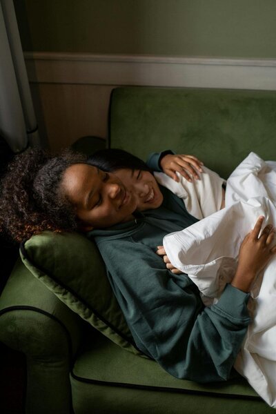 two women hugging while laying on a green couch