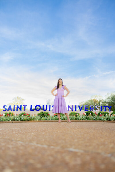 SLU senior in front of the saint louis university sign