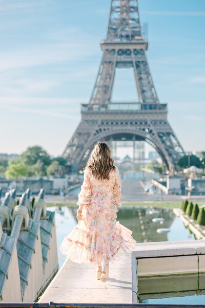 Mother in a floral dress facing away from the camera during a mother-daughter family photoshoot at the Eiffel Tower, captured at Trocadéro in Paris.