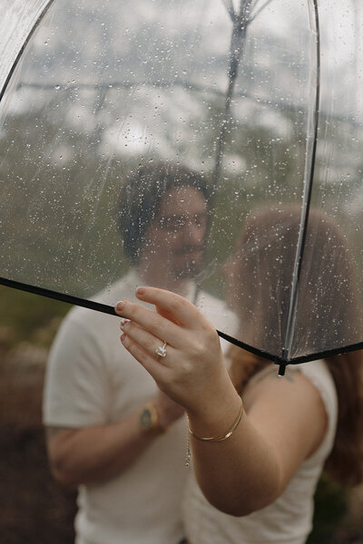 Couple posing with umbrella in the rain at The Mill At Fine Creek engagement session by RVA wedding photographer