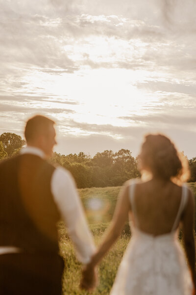 Bride and groom hold hands while facing the sunset during sunset photos on their wedding day