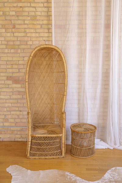 A tall back peacock chair and a small round rattan coffee table.