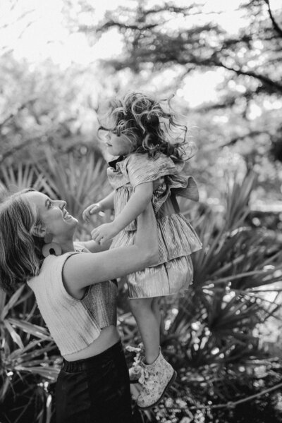 Mother holding little girl in the air in gardens at Austin family photoshoot