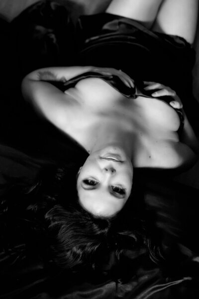 Woman laying on a bed looking up at the camera for her Toronto boudoir photography session.
