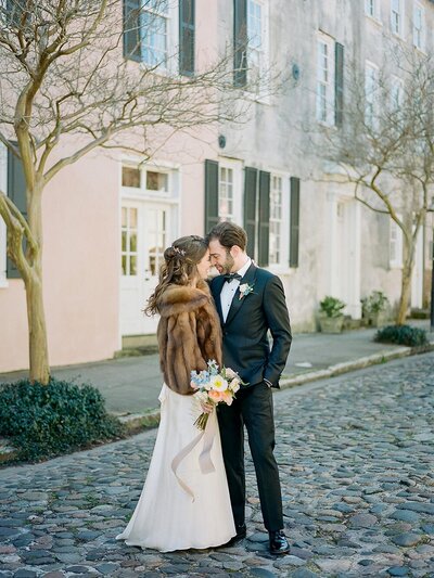 Charleston wedding day portraits on a cobblestoned street with historic houses in the background