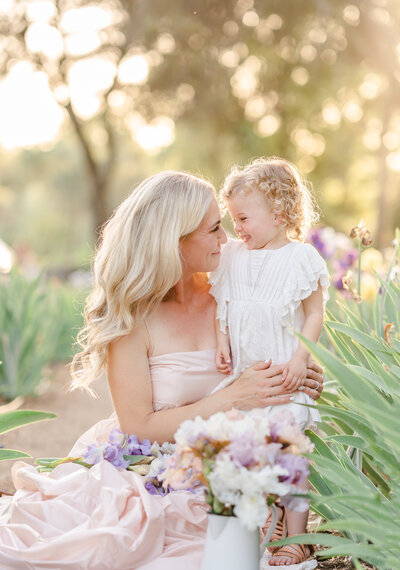 An expecting couple embraces and together hold  mama's belly standing in an almond blossom field during their Bay area maternity photography session by Light Livin Photography