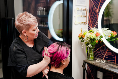 Hairstylist in salon consulting with a client with bright pink hair