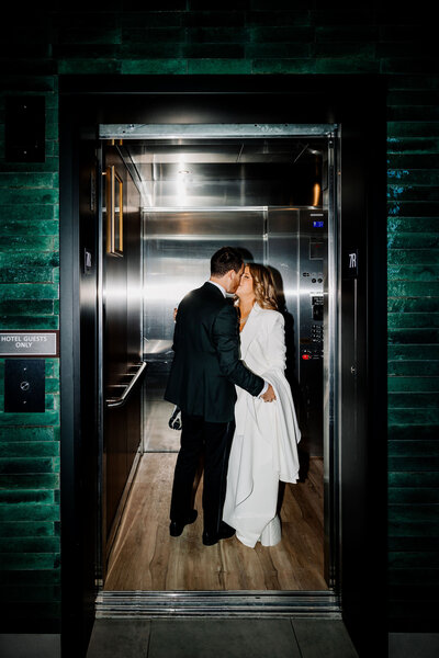 Bride and groom kissing in an elevator