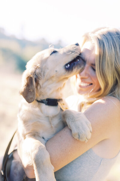 puppy kissing their person and the woman smiling