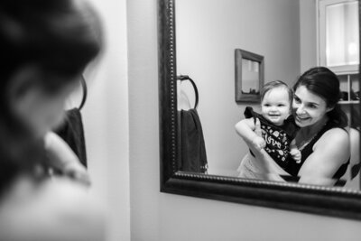 a baby and her mom looking at their reflection in the mirror