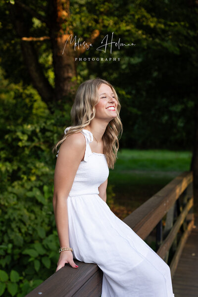 Highschool senior girl sits on bridge at University of Pittsburgh at Greensburg during candid moment.