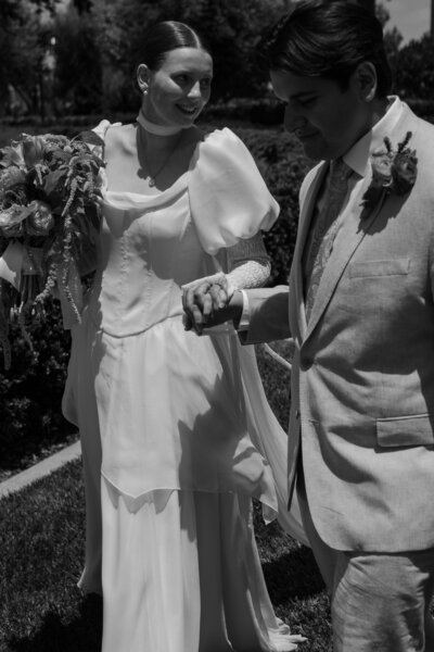 Yered holding Regan's hand and walking with her during their wedding at the Newport LDS Temple, in black and white.