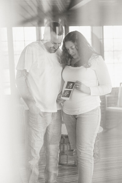Couple share an emotional moment looking at their ultrasound for their maternity photos in Bucks County PA