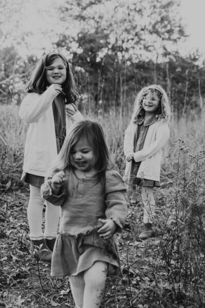 black and white candid family portrait with kids giggling and running towards camera