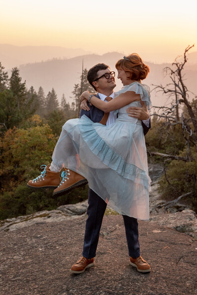 Groom holds his newlywed wife in a gorgeous sumer sunset in Yosemite.
