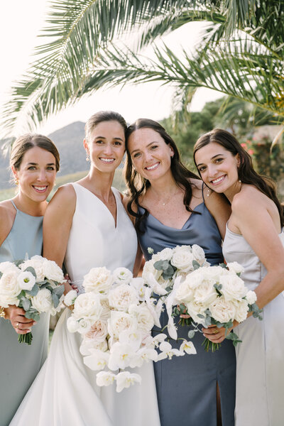 bride and bridesmaids in mixed dresses and white bouquets at wedding in mallorca