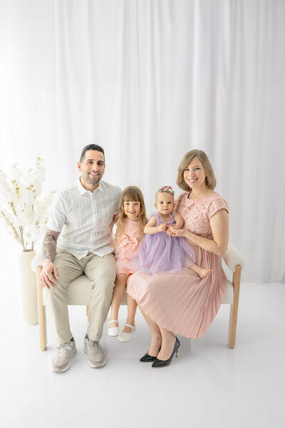 Family sitting together and smiling at camera  — photographed by Alliston and Barrie maternity, newborn, and family photographer.