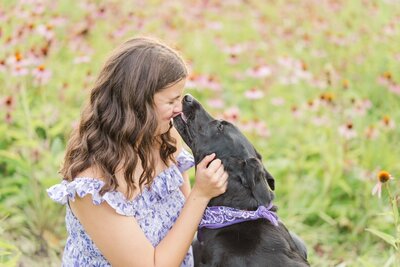 a high school girl smiling while her dog licks her on the face