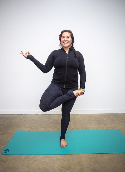 Yoga teacher Priscilla Luckhurst holds one legged yoga pose & smiles during 200 hour yoga teacher training