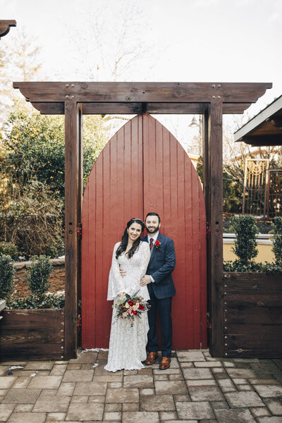 Stone House | Couple hugging and smiling in front of red door during wedding | Warren, New Jersey