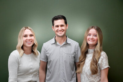 Family dentist Rustin Hawker smiles at Desert Hills Dental with two of his employees on either side of him.