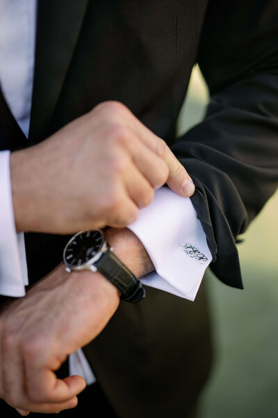 Closeup of the groom in his tuxedo fixing his cufflinks