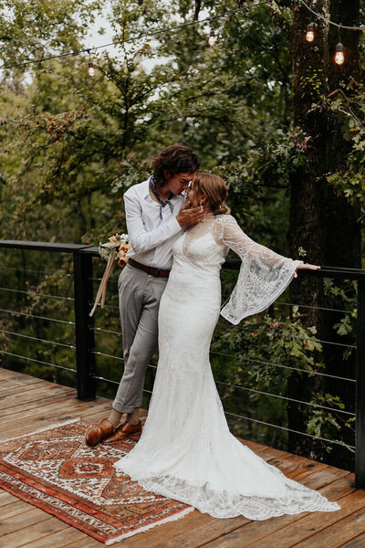 Bride and Groom standing on a bridge and leaning in for a kiss