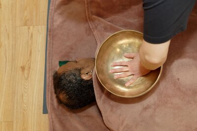 Leslie en train de pratiquer le massage neuro-musculaire au bol chantant sur un client. 