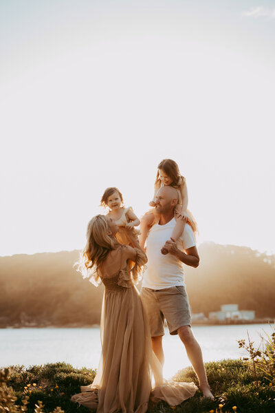 Family walking across coastal rocks at sunset, photographed by Sydney family photographer Sophie Lea.