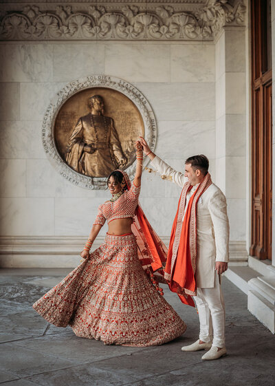 groom spins bride in indian wedding attire at hartford capital building photo by cait fletcher photography
