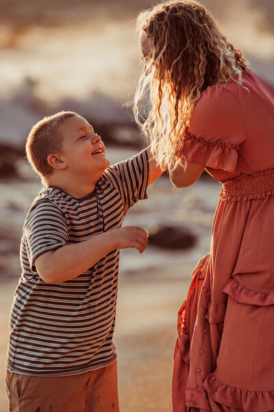 emotive lifestyle photograph of a mother and son on sunset beach