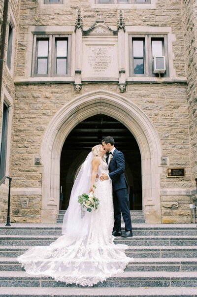 Bride and groom kiss on church steps