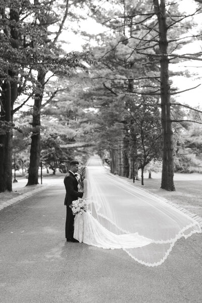 Bride and Groom kissing on driveway of the Ashford Estate with veil blowing in the wind