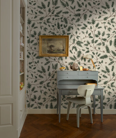 Soft clay colored wallpaper with symmetrical tiles in the form of hand drawn black Swiss crosses adorn the walls of a living room with a white couch and boho decor. Style bohemian, modern, vintage modern, whimsigoth,