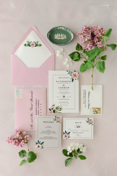wedding invitation with pink florals, greenery, and black typography