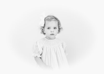 Black-and-white heirloom portrait of a young girl in a smocked dress.