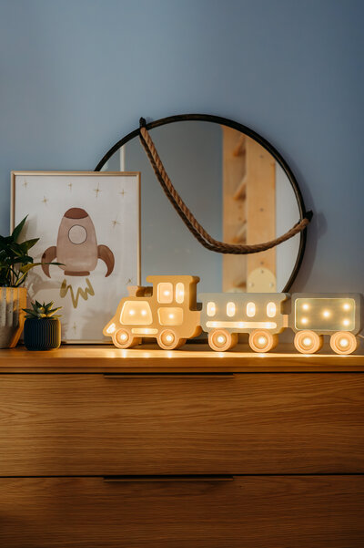 Lit wooden decorative train displayed on a dresser in a blueish grey room