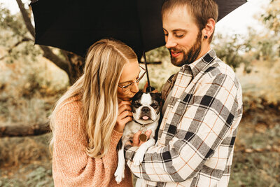 A couple snuggles in with their furbaby along the banks of the Missouri River during a family outdoor photoshoot.