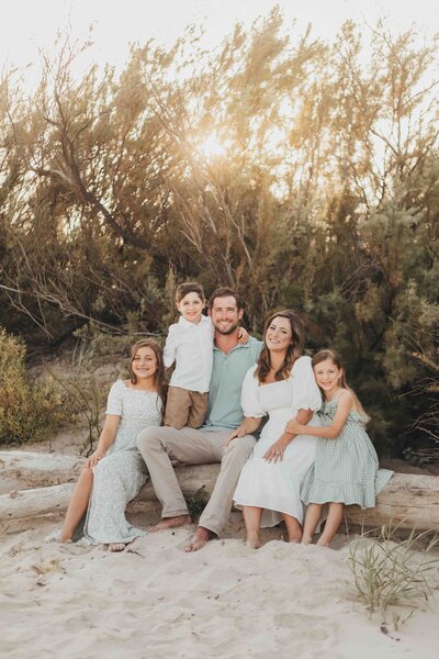 Elly brown, instagram influencer, and her family kneel down together at the park in houston texas, under trees with moss hanging down.