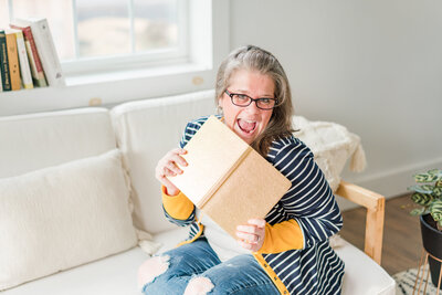 Lifestyle image of business owner smiling from behind a book she is reading