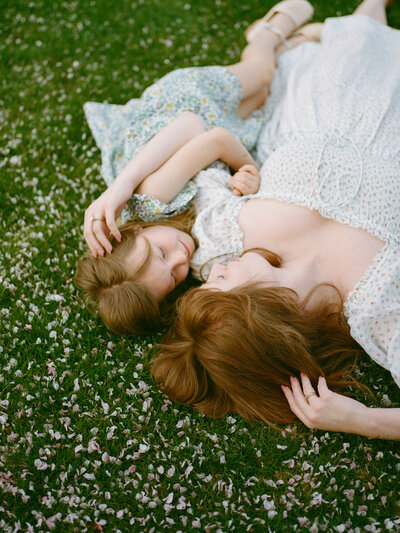 mother and daughter laying in flower petals at huntsville alabama photography session by fauna & film