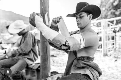 A cowboy adjusting his rodeo elbow braces, designed to protect the elbow joint during rodeo events.