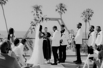 Bride and groom on balcony with the ocean and plam trees behind them in San Diego