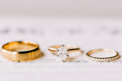 close up of bride and groom's engagement and wedding rings on top of invitation winx photo knoxville wedding photographer