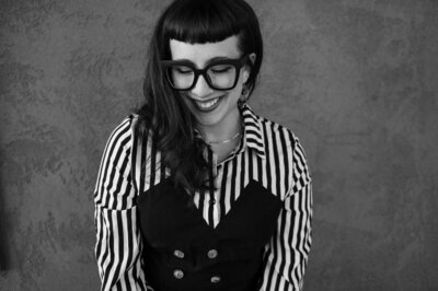 A black and white photo of Ashley Joyce smiling and looking towards the left side of the frame