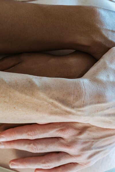 Close-up of two people’s arms and hands resting gently against each other in a moment of stillness.