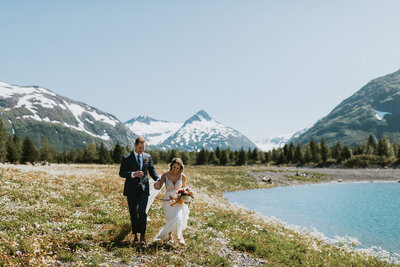 couple walking out on cliff over fall mountains as groom kisses the brides hand at arctic valley