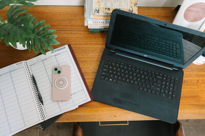 Phone sitting an a planner next to a laptop